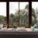 Outdoor-sitting-area-in-a-glass-enclosure-with-a-view-of-the-forest-and-the-ocean