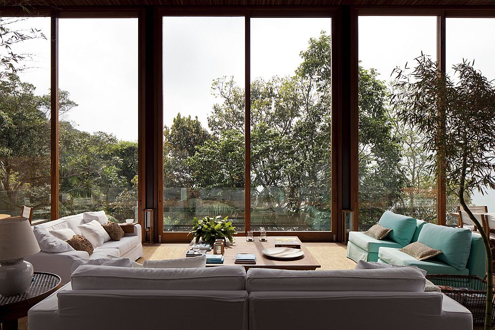 Outdoor-sitting-area-in-a-glass-enclosure-with-a-view-of-the-forest-and-the-ocean